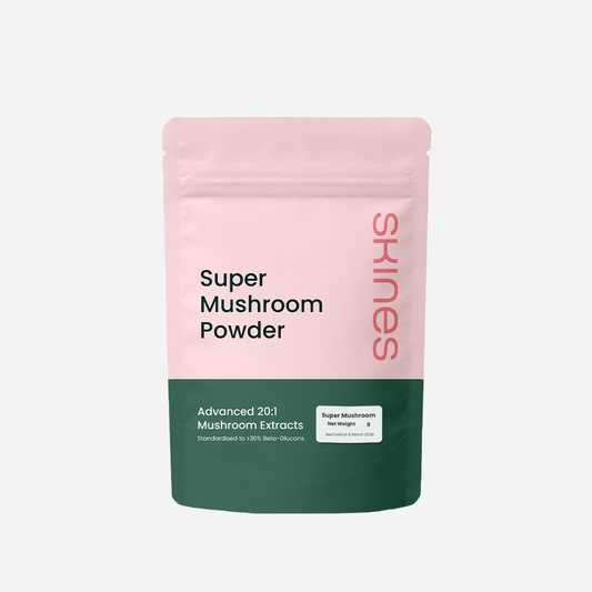 Pink and green package of SKINES Super Mushroom Powder (Signature Blend) on a light gray background